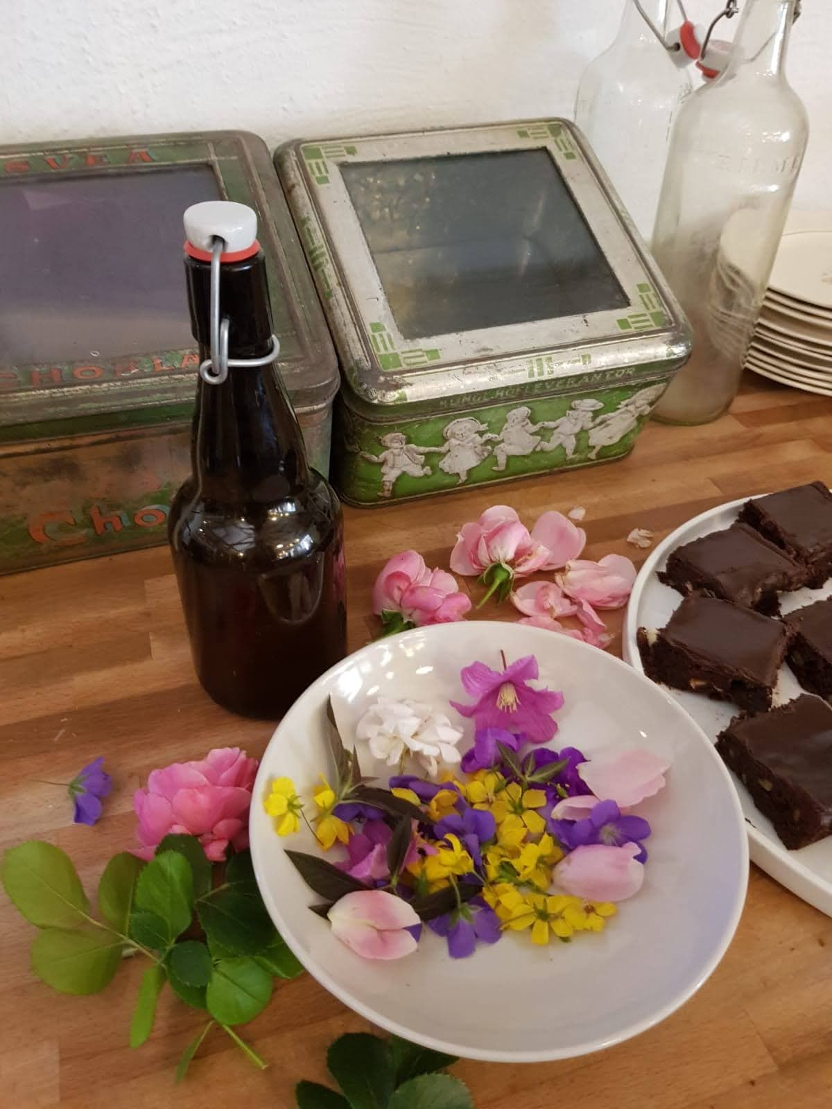 Färgglada blommor pryder disken bredvid ett fat med chokladkakor